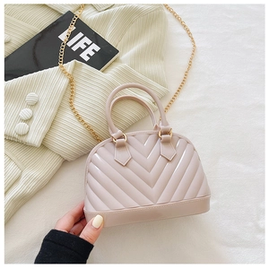 Detail of shell-shaped jelly handbag in pale pink with embossed V-textures and gold chain