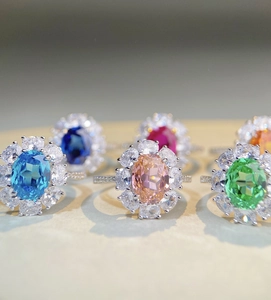 Macro shot of colorful oval halo rings with emerald, ruby, and blue sapphire stones