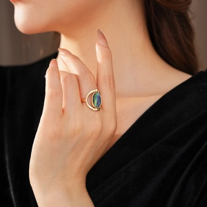 Detail of gold oval ring with iridescent shell inlay against a black velvet background