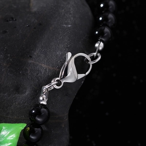 Macro detail of 316L stainless steel lobster clasp on black beaded lion head necklace