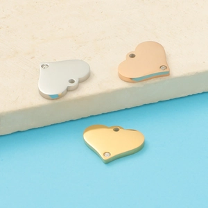 Macro detail of heart-shaped titanium steel charms with crystals in gold, silver, and rose gold