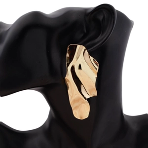 Chic irregular wavy gold metal earrings with a polished finish on black model stand