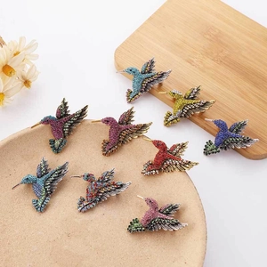 Exquisite hummingbird brooches with vibrant rhinestones in multiple colors on a ceramic tray