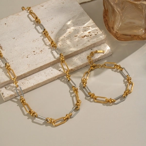 Detail of gold and silver mixed color chain necklace and bracelet on stone blocks