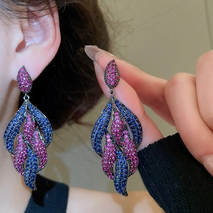 Close-up of luxury leaf earrings with blue and pink zircons worn by a model