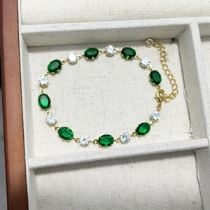 Élégant bracelet en émeraude dorée avec zircons ovales verts et clairs dans un écrin