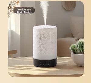 Detail of white crackle diffuser with dark wood base emitting mist on a desk