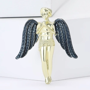 Macro view of gold angel brooch with black enamel wings and detailed feather texture