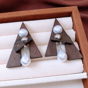 Close-up of vintage geometric earrings with wood triangles and pearl drop details