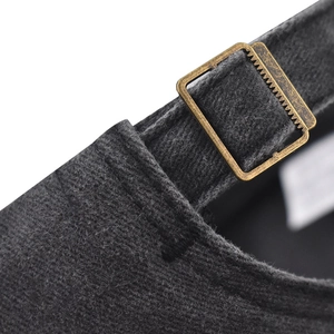 Detailed close-up of the vintage bronze metal buckle and washed grey twill fabric on cap