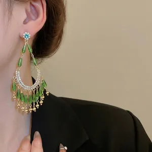 Boucles d'oreilles fleur avec glands gouttes vertes et cristaux sur modèle