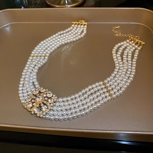 Close-up of multilayer pearl necklace with gold crystal square buckle on a tray