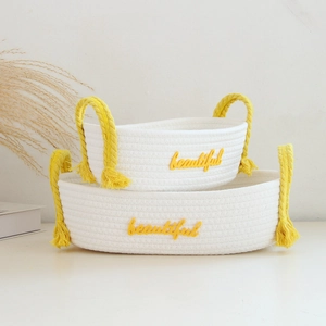 Detail of white cotton rope storage baskets with yellow handles and beautiful embroidery