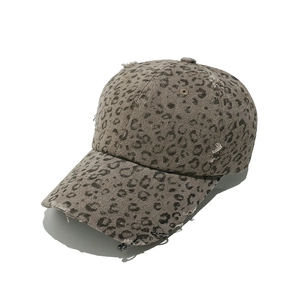 Detail of leopard print baseball cap with distressed holes and metal rings on the brim