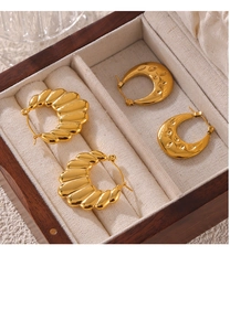 Detailed close-up of gold-plated U-shaped earrings with textured patterns in a jewelry box