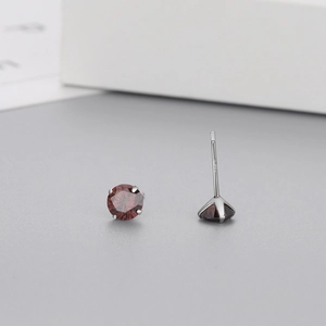 Detailed macro view of S925 sterling silver stud earring with red zircon in 4-prong setting