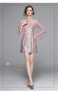 Détail d'une robe en dentelle rose avec broderie délicate, volants et col montant