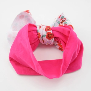 Detail of baby nylon headband featuring large pink and floral print bow on white background