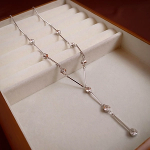 Detail of silver Y-shaped long necklace with crystal bars in a beige jewelry box