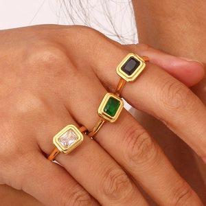 Dettaglio di tre anelli placcati in oro 18K con zirconi verdi, neri e bianchi incastonati