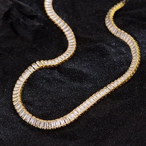 Elegant gold tennis necklace with rectangular zircon stones on a sparkling black background