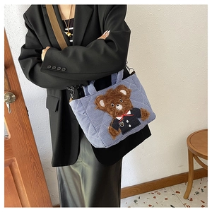 Close-up of blue plaid children handbag featuring a cute plush brown bear decoration