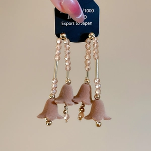 Dettaglio di orecchini vintage con fiori floccati e lunghi pendenti dorati