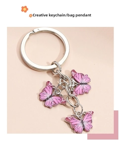 Detailed macro of a silver metal keychain featuring three gradient pink butterfly charms