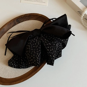 Detail of elegant black leopard print bow hair scrunchie on a premium wooden tray