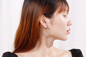 Macro detail of silver stainless steel hoop earrings featuring textured beaded surface