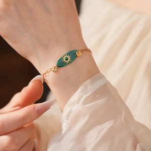 Détail d'un bracelet vintage en chaîne dorée avec pierre verte sur le poignet d'un mannequin