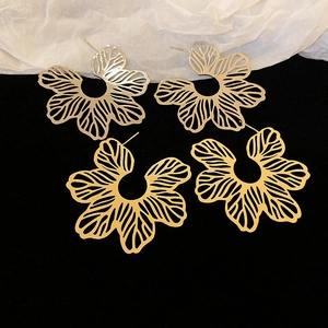 Exquisite hollow floral stud earrings in gold and silver finish on velvet display