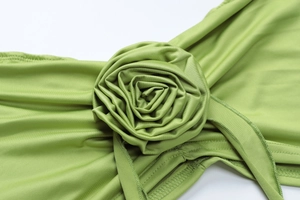 Detail of green knit dress featuring a handcrafted 3D fabric rose flower and pleated texture