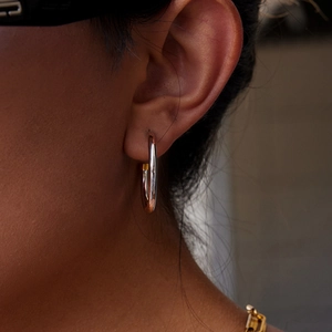 Close-up of elegant silver stainless steel hoop earrings worn on model's left ear