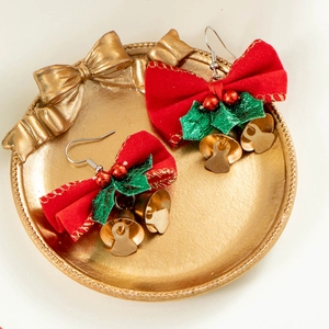 Vue détaillée de boucles d'oreilles nœud de Noël avec feuilles et cloches dorées