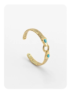 Detail of snake scale texture and blue stones on vintage golden open wrap bracelet