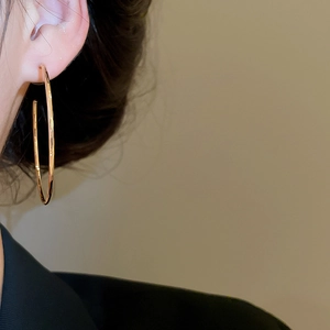 Grande créole dorée polie sur modèle vue de côté montrant un design minimaliste épuré