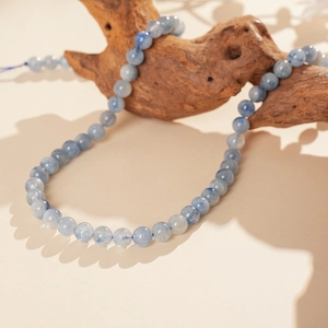 Detailed view of blue stone beaded bracelet wrapped on natural dark wood with soft shadows