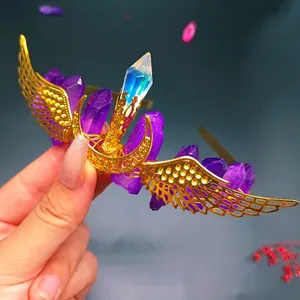 Detail of handmade gold crown featuring purple crystals and intricate metal wing accents