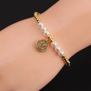 Detail of beaded pearl bracelet with a sparkling gold smiley face charm on a wrist