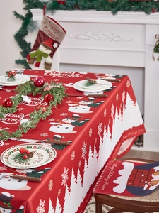 Detail van rood kersttafelkleed en stoelhoezen met sneeuwpop en winterse decoraties