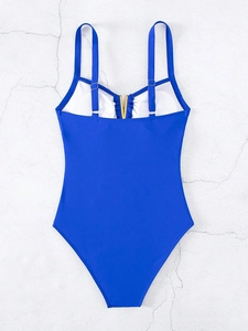 Detail of royal blue one-piece swimsuit featuring a gold V-shaped metal hardware at neckline