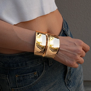 Close-up of irregular wide golden cuff bracelet with high-polish mirror finish on wrist
