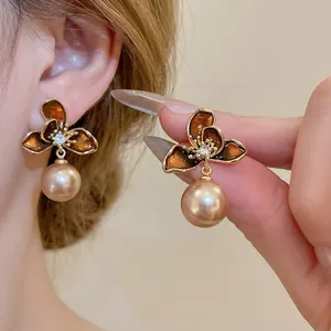 18K gold plated flower drop earrings with brown enamel and pearls worn by a model