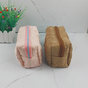Detailed view of quilted makeup bags in pink and brown with high-quality zipper hardware