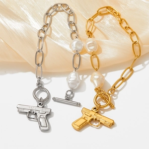 Baroque pearl bracelets in gold and silver with pistol charms on light silk fabric