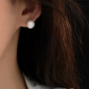 Close-up of 8-10mm white freshwater pearl stud earring worn on a model's ear