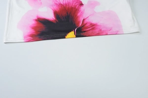 Detailopname van de zoom met paarse bloemenprint op witte stof en strakke stiksels