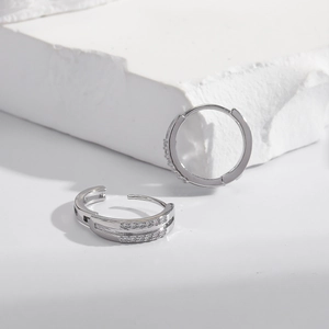Silver hoop earrings with double row cubic zirconia on geometric white props