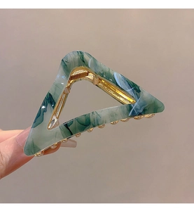 Detail of triangle hair claw with green marble texture and golden metal spring clasp